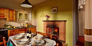 Un coin repas agrémenté d’une cheminée en briques, de meubles en bois et d’une table dressée pour quatre personnes.