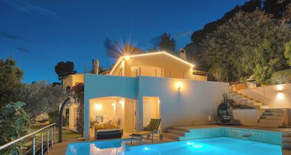 Villa with panoramic view over the Cap d'Antibes swimming pool in lush greenery.