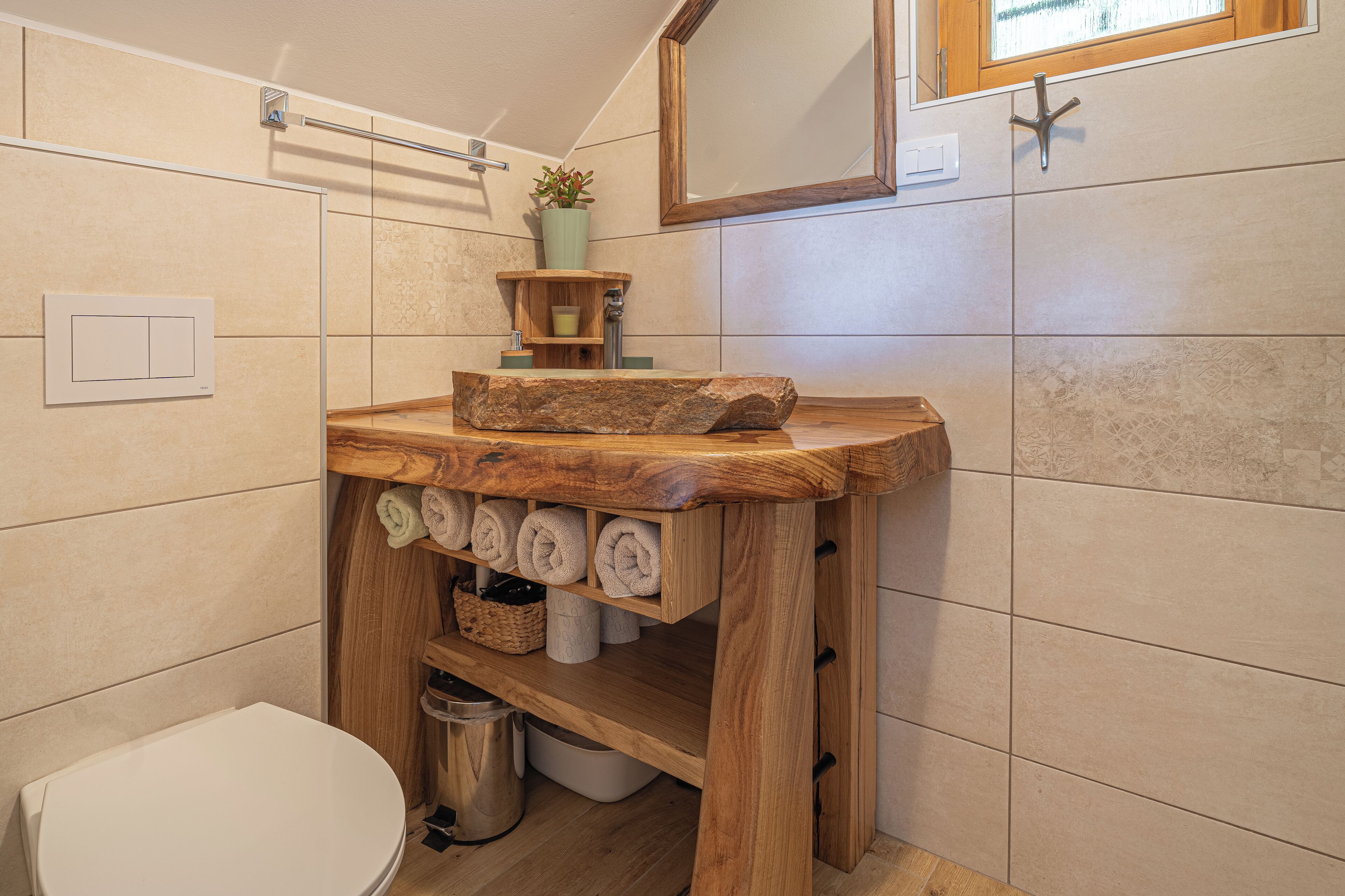 Un baño con tocador de madera, inodoro y espejo.