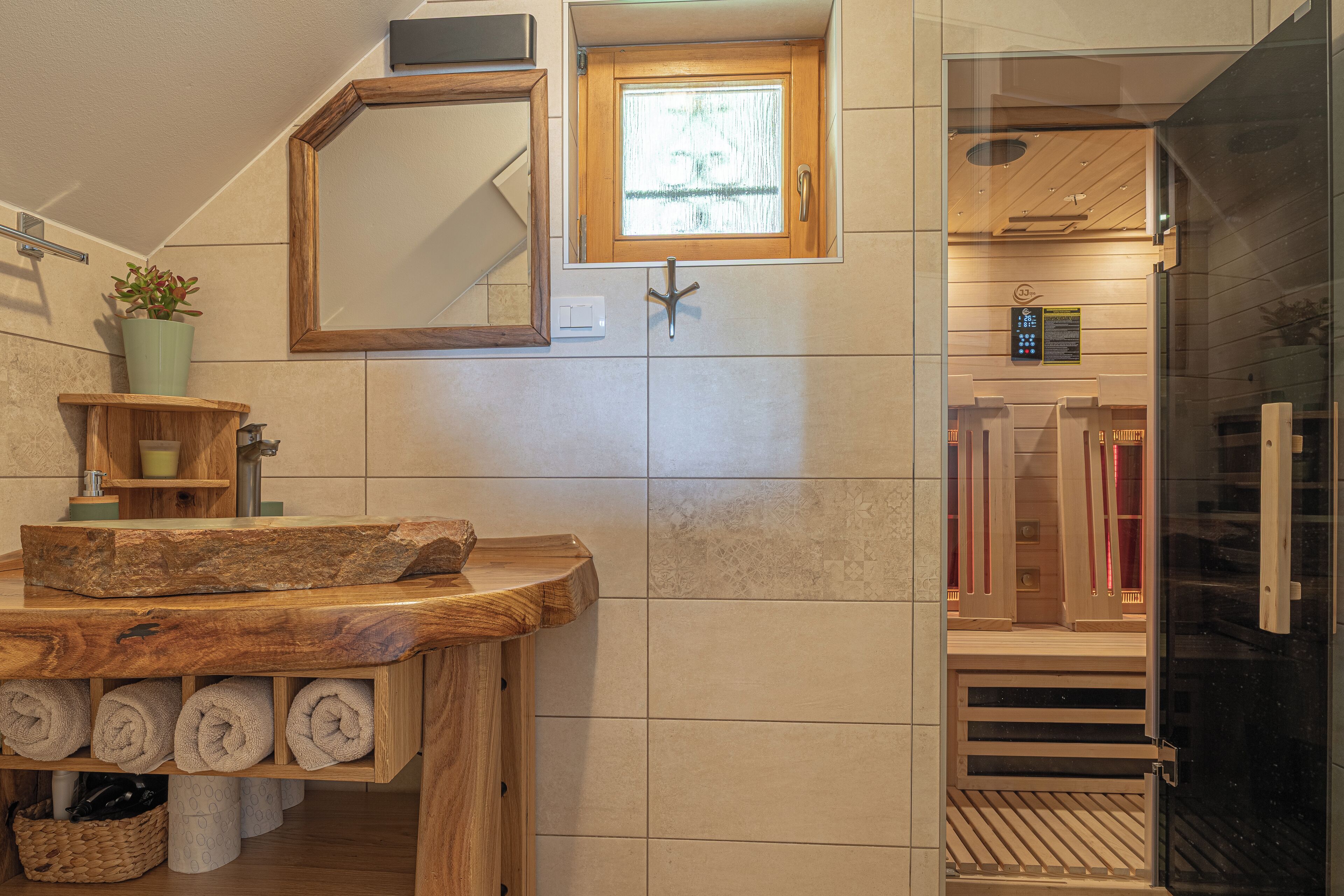 Un baño con tocador de madera, espejo, ventana y zona de ducha.