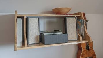 Uno scaffale in legno con un giradischi, libri e una chitarra.