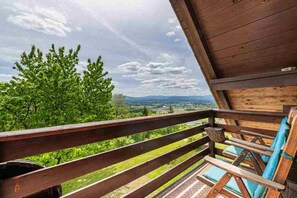 Une terrasse en bois offrant une vue sur un paysage verdoyant et des montagnes lointaines.