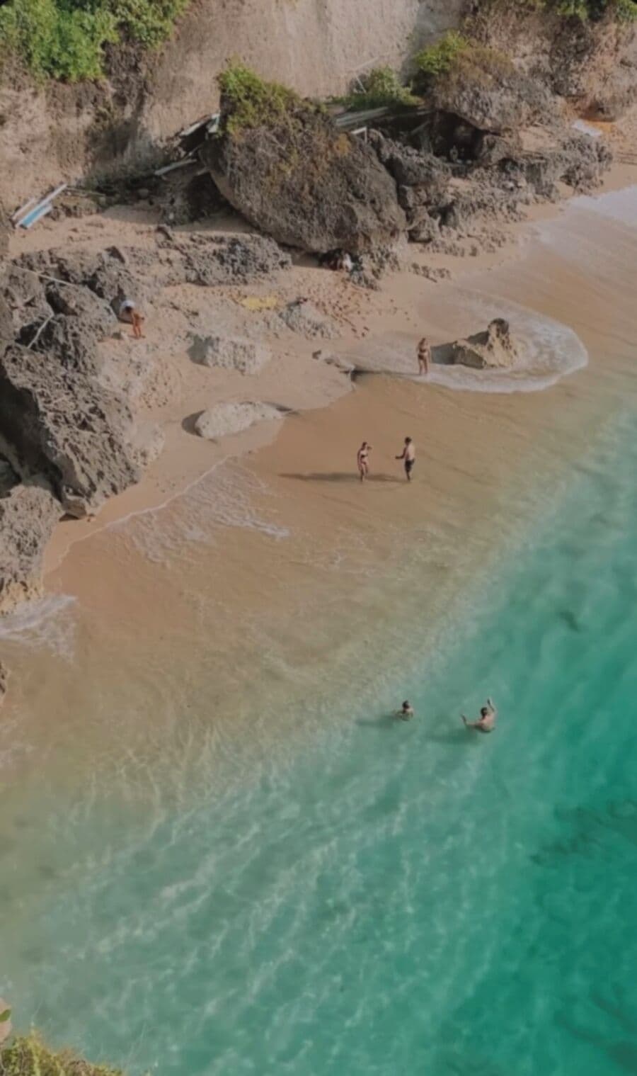A beach with rocky terrain and clear turquoise water.