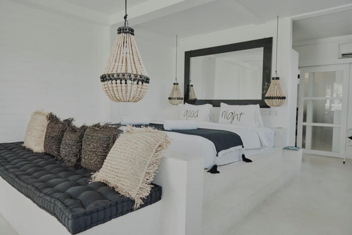 Une chambre à coucher moderne avec un grand lit, un canapé foncé et un grand miroir.