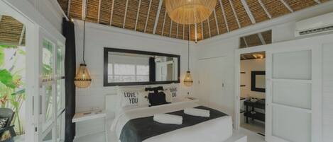 A bedroom with a bed, a large mirror, a ceiling fan, and a view of a bathroom.