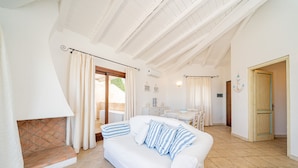 Amplia sala de estar con un sofá blanco, una chimenea y un comedor.
