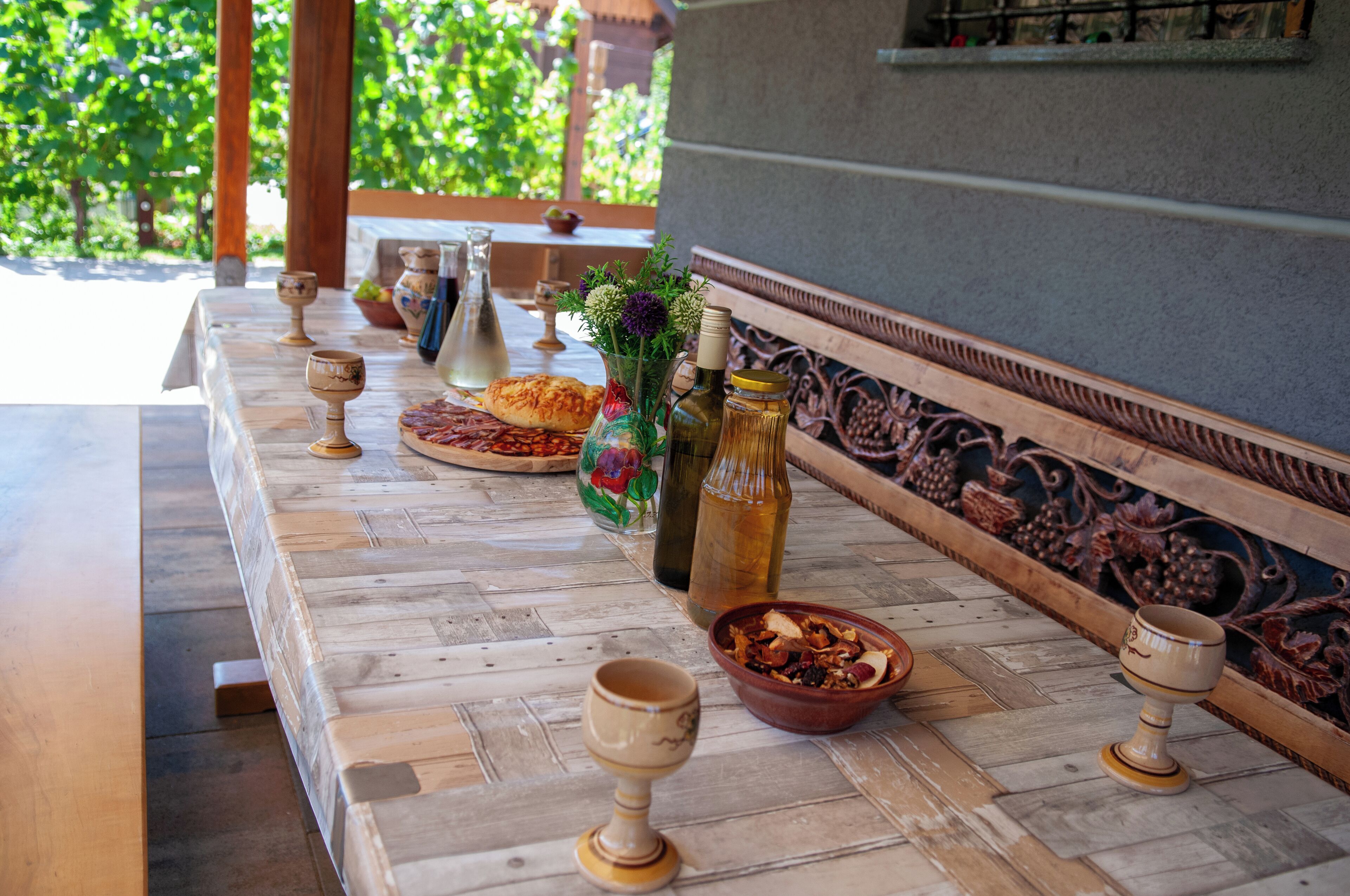 Una larga mesa de madera con varios objetos, como un jarrón, una botella y cuencos.