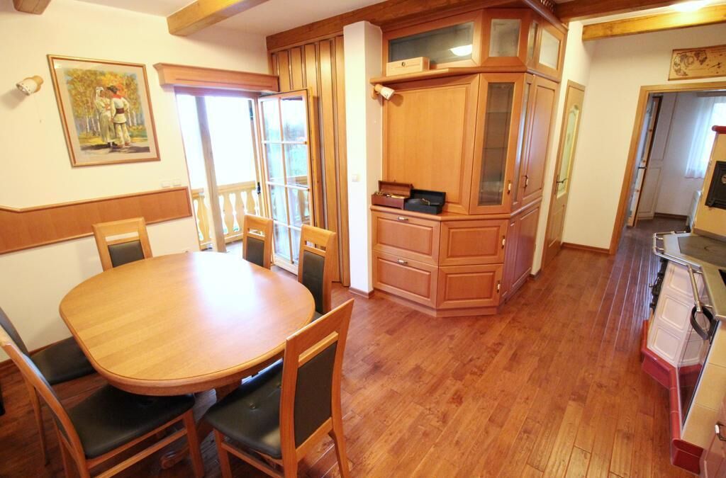Un comedor con mesa y sillas de madera, una cocina con armarios de madera y un cuadro en la pared.