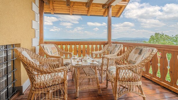 A balcony with wicker furniture and a table, wooden railing, and a view of the landscape. - Vineyard Cottage Stepan (Crnomelj)