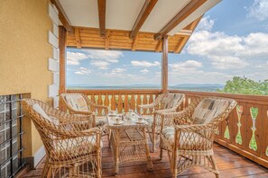 A balcony with wicker furniture and a table, wooden railing, and a view of the landscape. - Vineyard Cottage Stepan (Crnomelj)