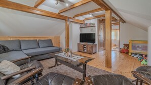 A loft-style living room with a sofa, coffee table, and wooden beams. - Vineyard Cottage Stepan (Crnomelj)