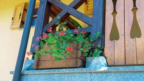 A wooden structure with a window, a wooden bench, and a planter with red flowers. - Vineyard Cottage Stepan (Crnomelj)
