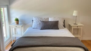 Une chambre à coucher avec un grand lit, une table de chevet, une lampe et une plante en pot.