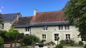 A stone building with a tiled roof, a wooden fence, and a garden with a pathway. - La Balastière (Beaumont-en-Veron)