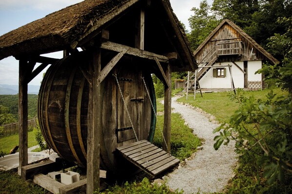 Eine rustikale Holzhütte mit einem Reetdach und einem Holzfass.