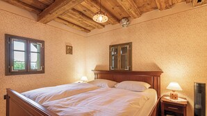 Quarto com cama de madeira, duas mesas de cabeceira com luminárias, um espelho e um ventilador de teto.