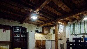 Uma cozinha rústica com vigas de madeira, um armário com portas de vidro, uma pia e um relógio na parede.