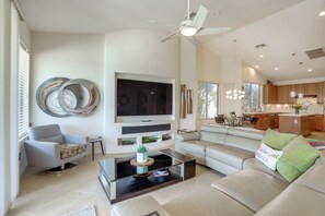 A modern living room with a flat-screen TV, a ceiling fan, a sofa, and a coffee table. - Pool, Golf Cart! Home in 55+ PebbleCreek Community (Goodyear)