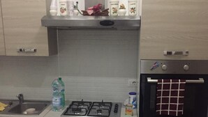Une cuisine moderne équipée d’une cuisinière à gaz, d’un four encastré, d’un évier et d’un plan de travail sur lequel sont disposés divers objets.
