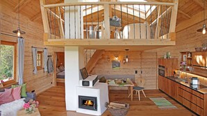 Um amplo quarto em estilo loft com interior de madeira, lareira, sala de jantar e cozinha.