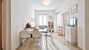 A modern living room with a dining area, a TV, and a bookshelf.