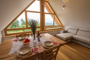 Dine amidst a lush landscape view from the high ceilinged dining area with a table set for four.