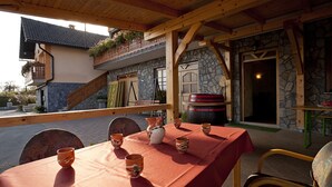 An outdoor dining area with a red tablecloth, stone walls, wooden beams, and a stone staircase. - Tourist Farm Skrbina (Smarjeske Toplice)