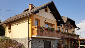 A two-story building with a stone facade, wooden balcony railings, and flower boxes. - Tourist Farm Skrbina (Smarjeske Toplice)