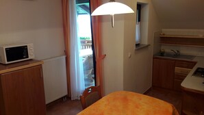A compact kitchen with a microwave, a dining table, and a small sink. - Tourist Farm Skrbina (Smarjeske Toplice)