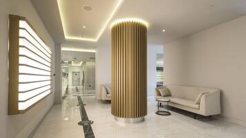 A modern hotel lobby with a central column, a sofa, and a glass partition.