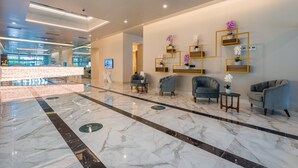 A modern lobby with marble flooring, seating areas, and wall-mounted shelves with potted plants. - Orbi City Hotel Official (Batumi)