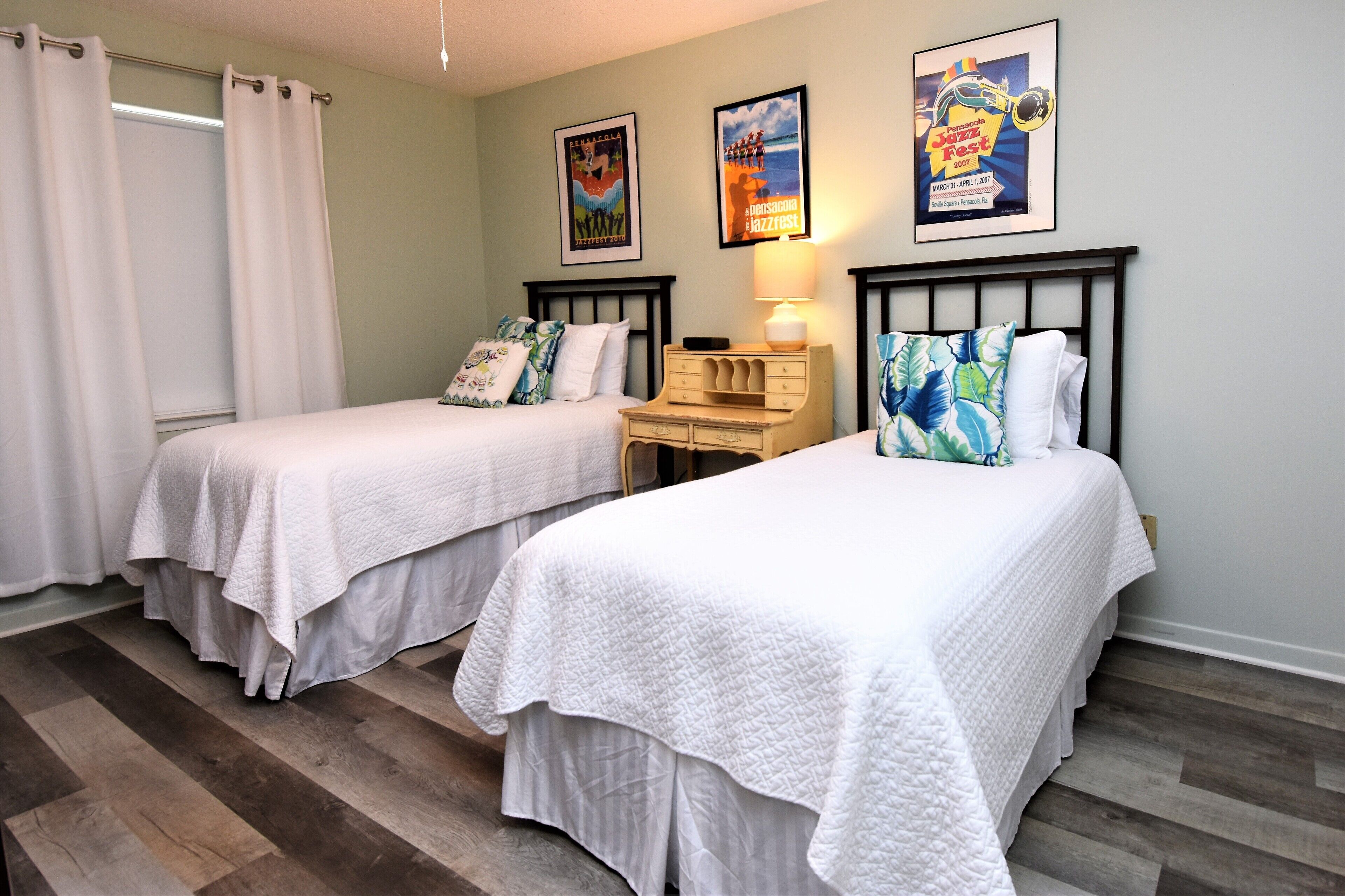A bedroom with two single beds, a nightstand, and a wall-mounted lamp.
