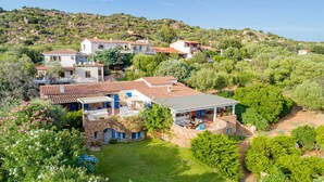 A hillside property with multiple buildings, including a house with a stone facade and a covered patio area. - Casa di Nonna Anna (Olbia)