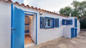 A building with a white exterior and blue shutters, featuring a door and windows with shutters.