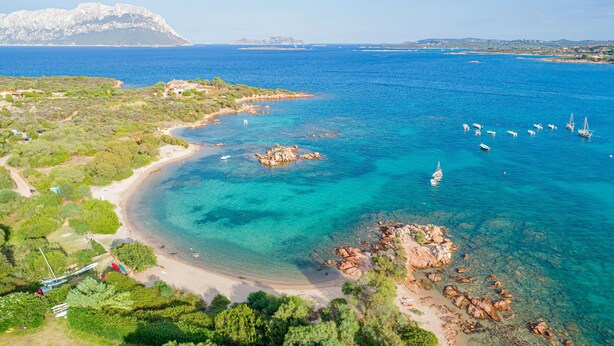 An aerial view of a coastal area with clear blue waters, rocky shores, and boats. - Casa di Nonna Anna (Olbia)