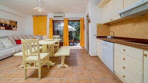 Un espace de vie compact comprenant un coin repas, une cuisine et une vue sur l’extérieur.