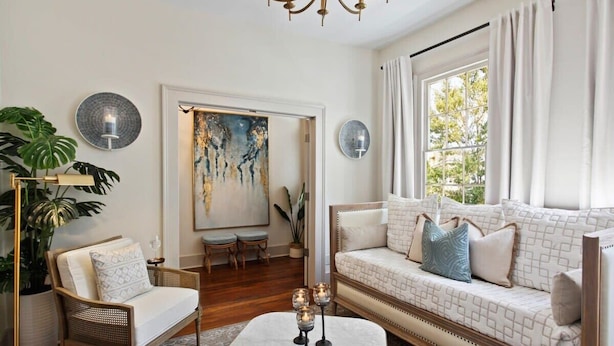 A living room with a sofa, armchair, and a coffee table. There are two wall sconces and a chandelier.