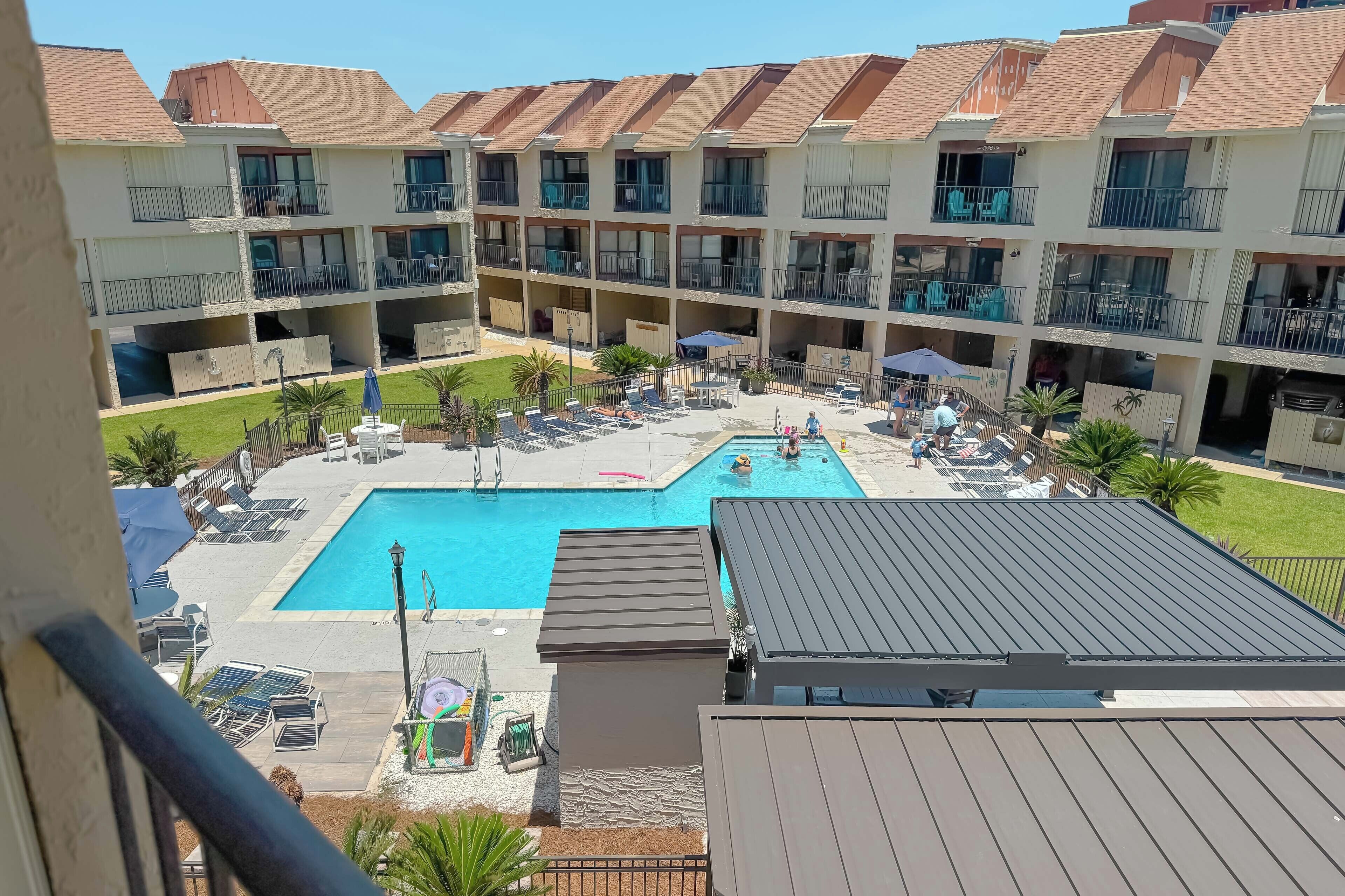 A multi-story hotel with a swimming pool, outdoor seating, and balconies.