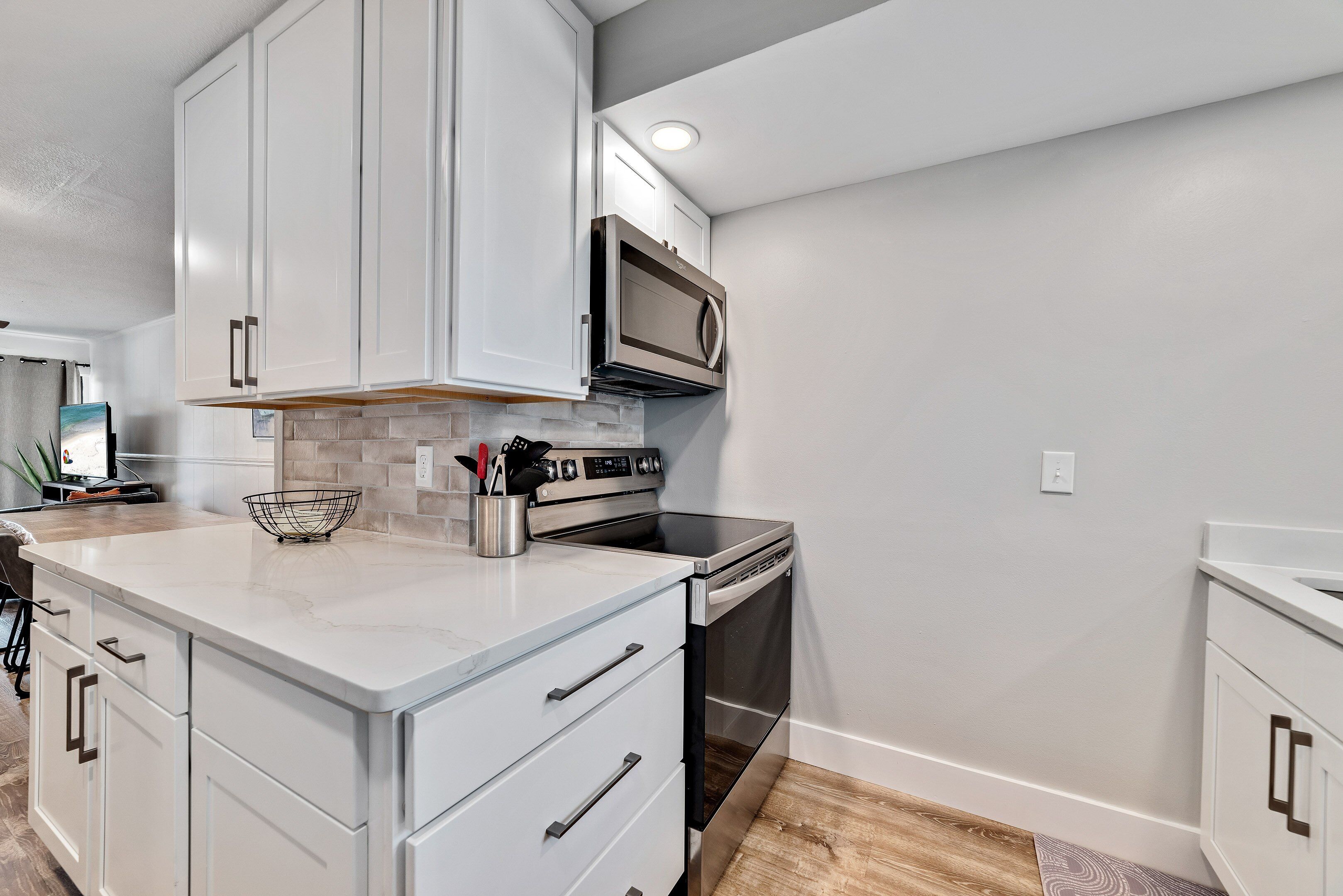 A modern kitchen with white cabinetry, a built-in microwave, and stainless steel appliances.