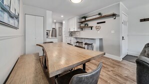 Una cocina moderna con armarios blancos, una mesa de comedor de madera y taburetes de bar.