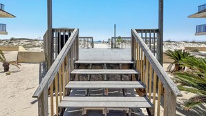Una escalera de madera que lleva a una zona de playa con cielo despejado.