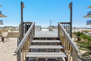 A wooden staircase leading to a beach area with a clear sky.