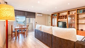 Een moderne woonkamer met een bank, een eettafel, stoelen, een televisie en een boekenkast.
