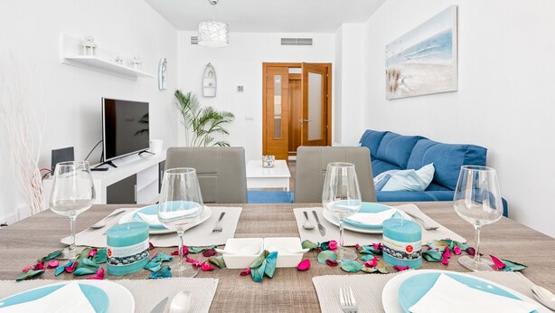 A dining area with a table set for four, a television, and a sofa in the background. - RELAX BY THE SEA, POOL, WIFI A / C. (Rincón de la Victoria)