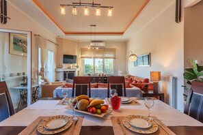 Un coin repas avec une table dressée pour deux personnes, un plateau de fruits et une boisson rouge.