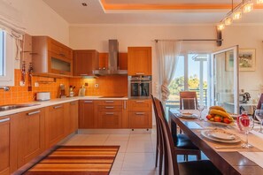 Une cuisine moderne avec des meubles en bois, un four encastré et un coin repas avec une table dressée pour deux personnes.