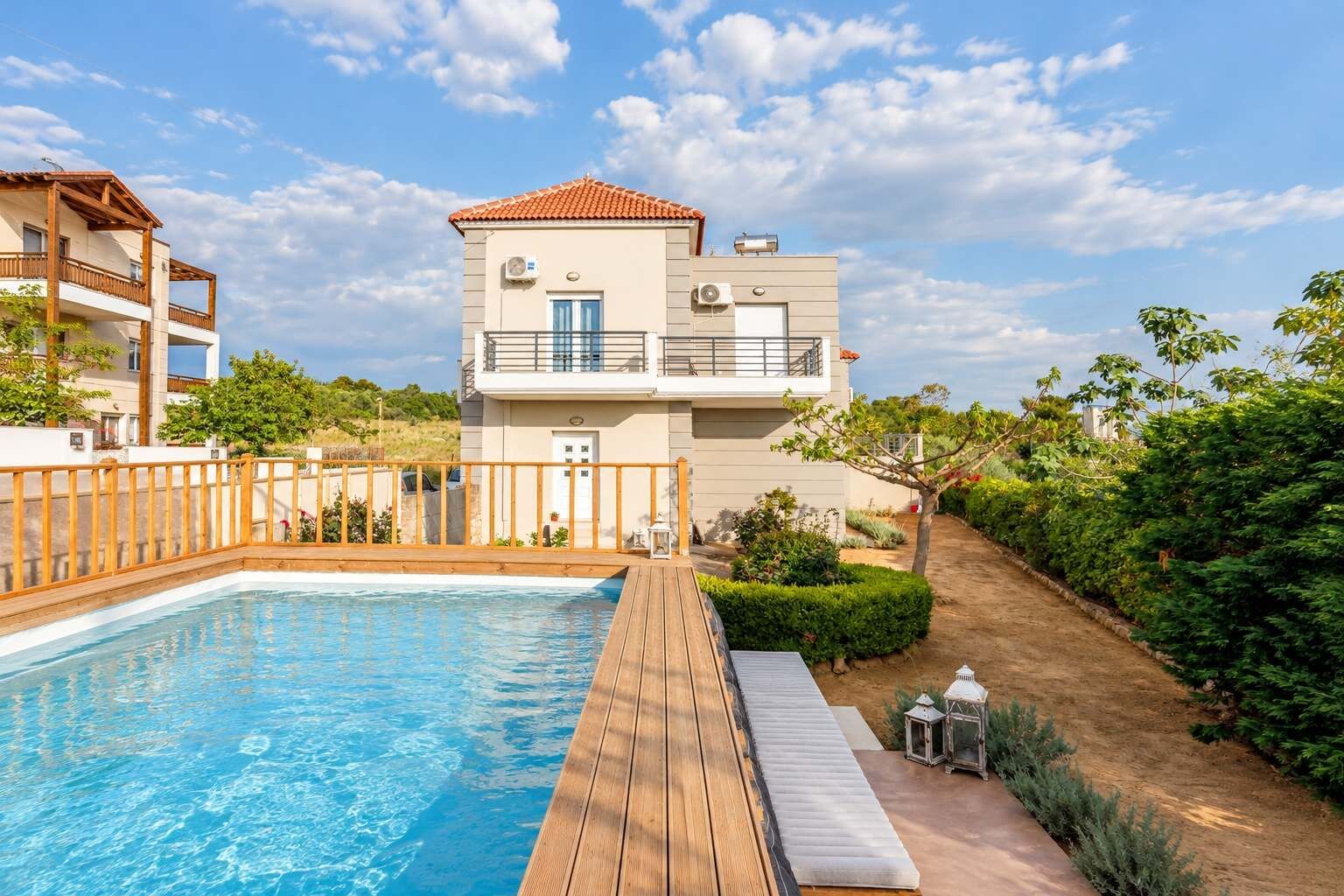 A two-story building with a swimming pool, wooden deck, and a garden area.