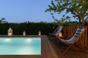 Zwembad met houten terras en lantaarns.