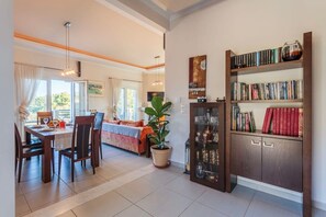 Un comedor con una mesa dispuesta para dos personas, un sofá y una estantería con libros y objetos decorativos.