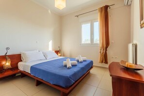 Une chambre d’hôtel comprenant un lit, une table de chevet, une fenêtre avec des rideaux et un climatiseur fixé au mur.